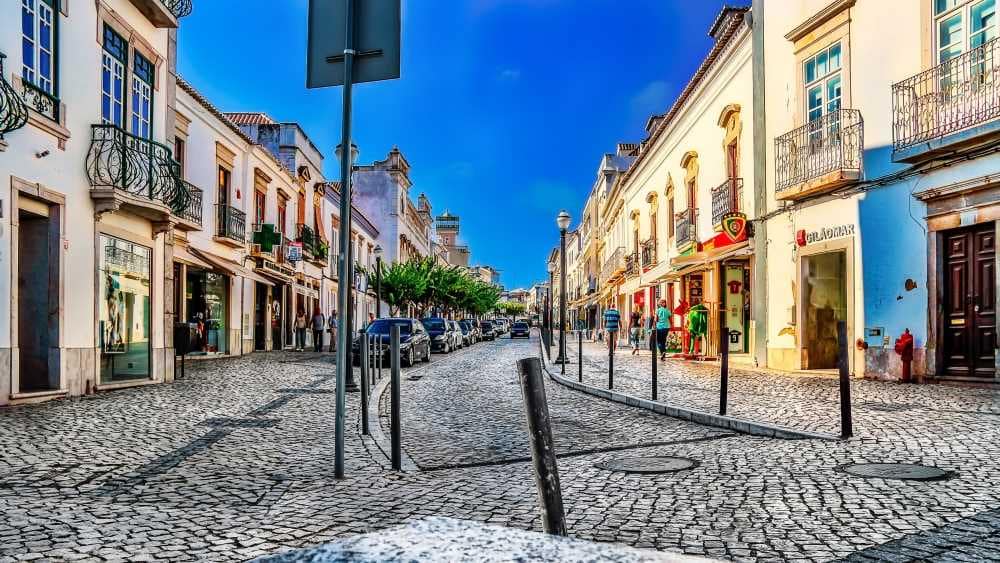 A narrow traditional street in Tavira Algarve with white houses and flowers
